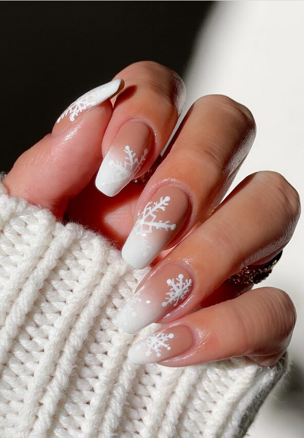 Nude nails with delicate white snowflake designs for a classic winter manicure
