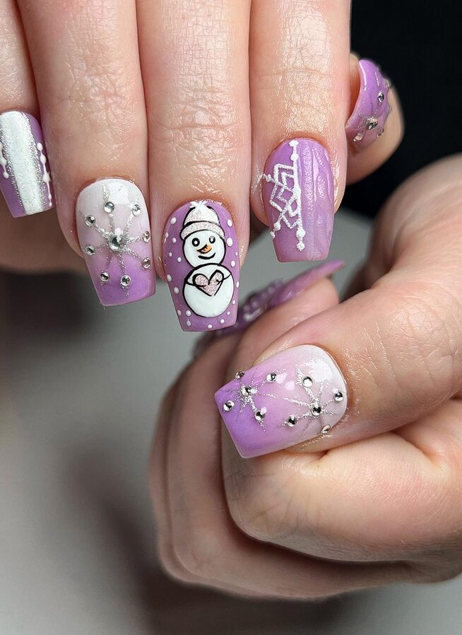White and purple nails decorated with snowmen and snowflakes