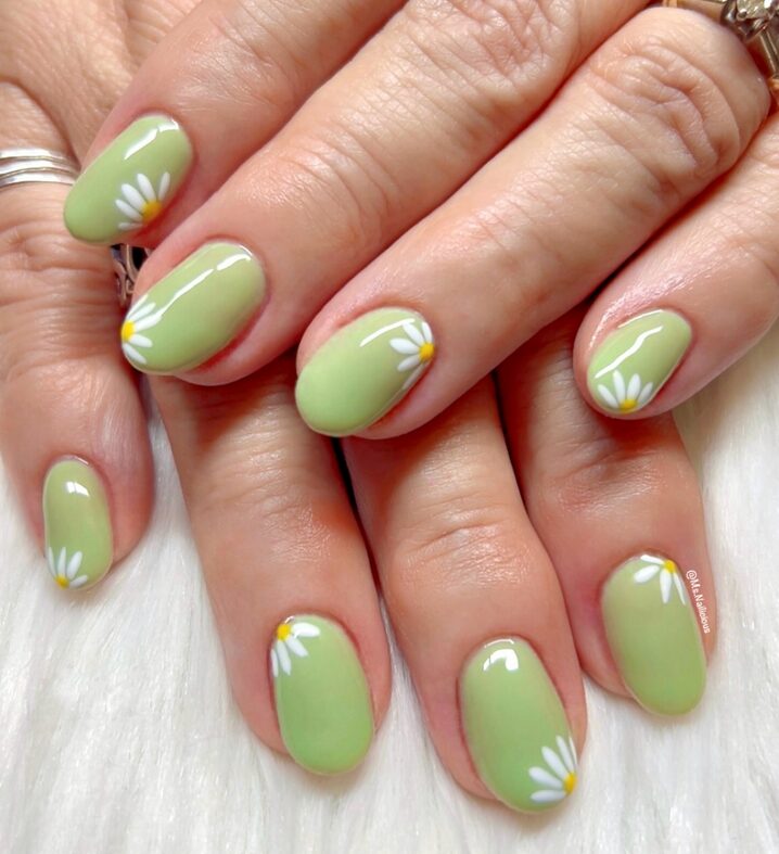 Soft mint green nails with small floral artwork in white or pastel hues