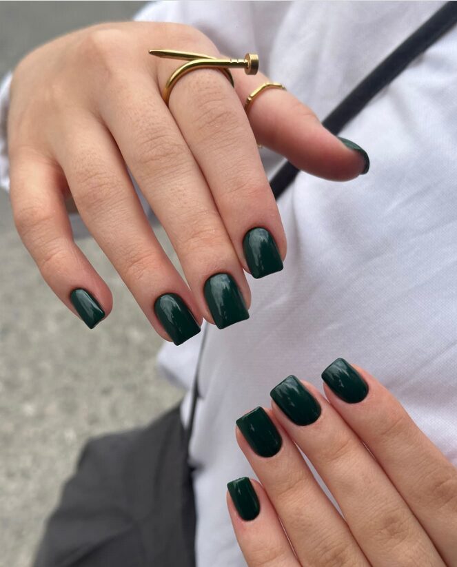 Short rounded nails painted in deep forest green gloss