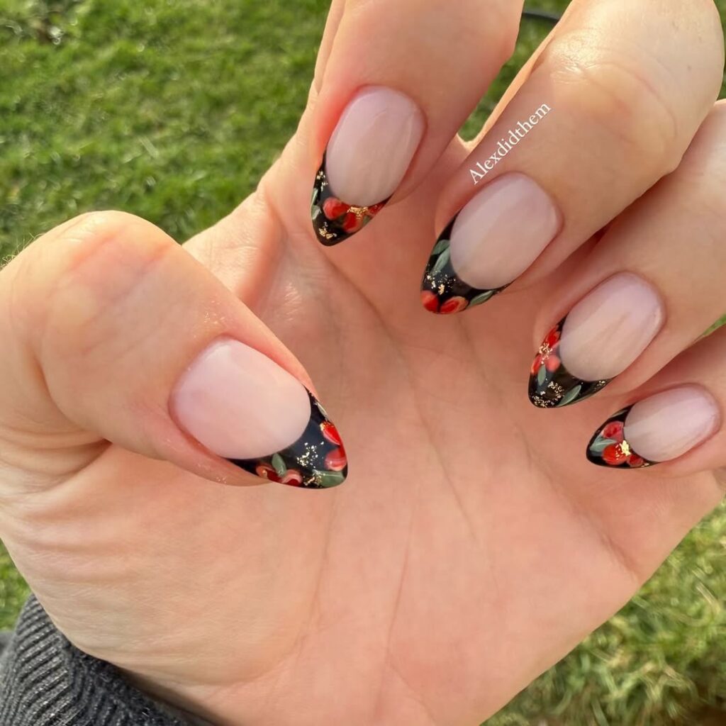 nails with black french tips featuring red flowers and gold foil