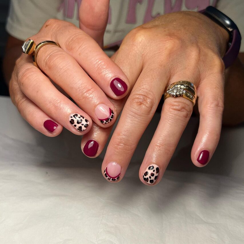 Short burgundy nails with pink accents and leopard-print details