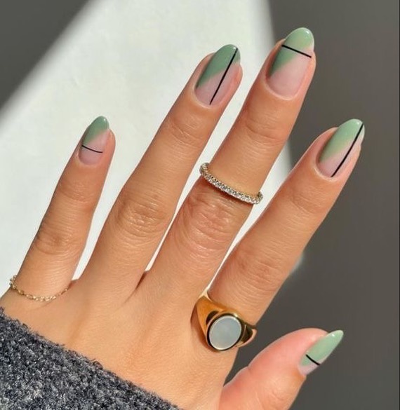Oval nails with sage green French tips and a thin black vertical line down the centre