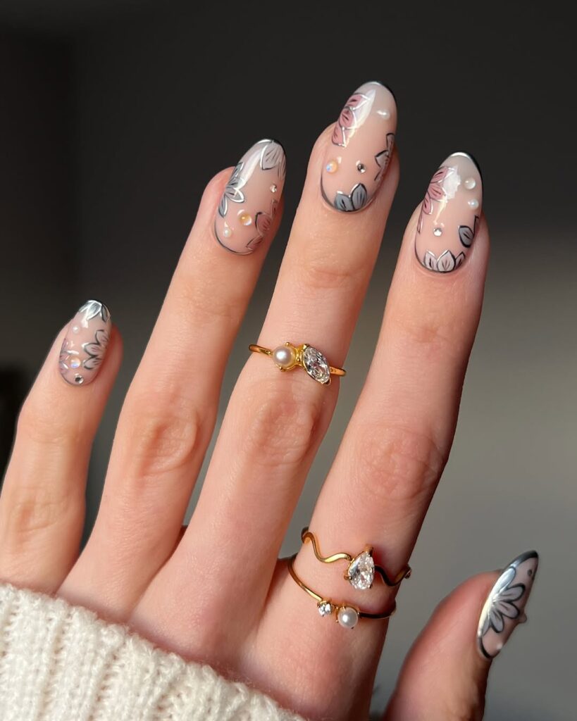 nails with sheer nude base, black outline and silver chrome floral art