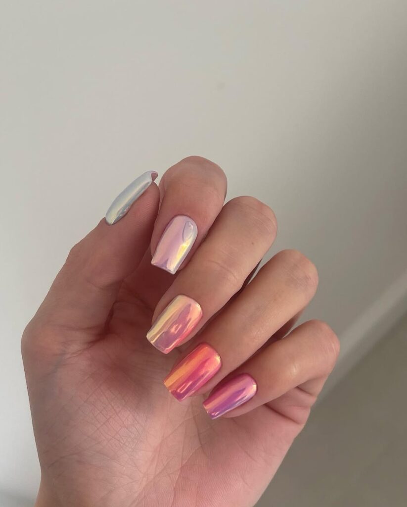 nails in gradient chrome shifting from white to lavender to orange to pink
