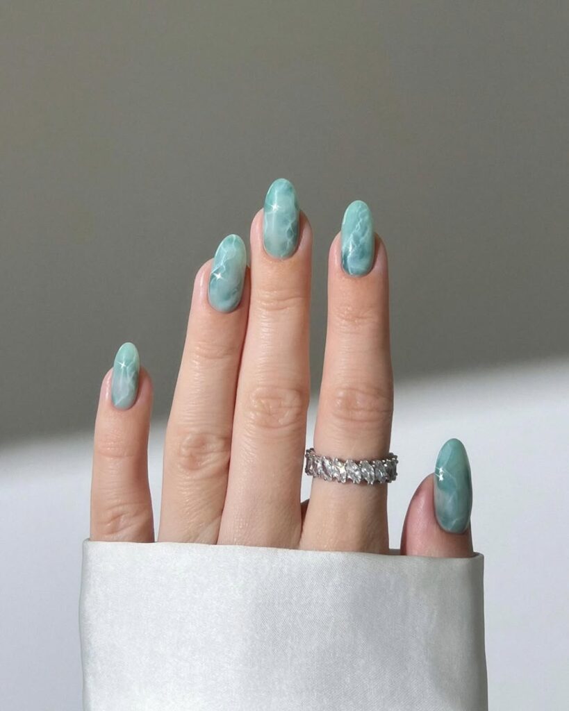 nails in teal chrome with a white marble wave pattern