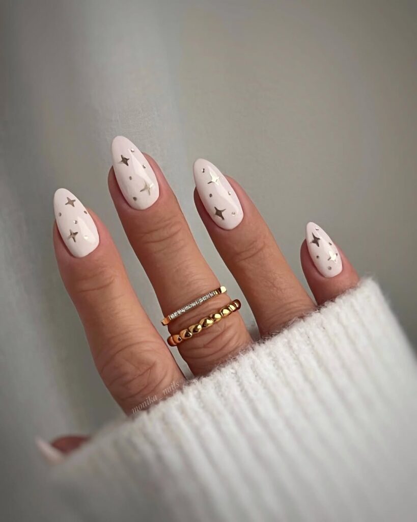 nails in soft white chrome with gold star and dot embellishments
