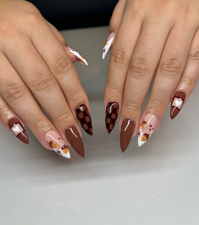brown and nude nails with fall-themed designs including acorns, white hearts, stars