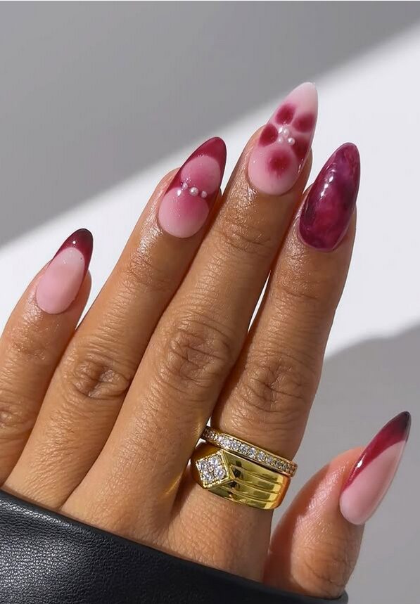 Berry-toned nails featuring deep red and blush gradients with abstract floral patterns