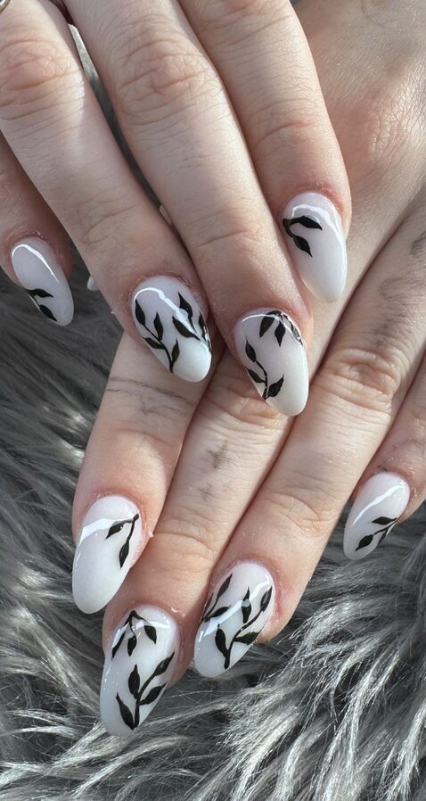 White almond nails with minimal black leaf designs
