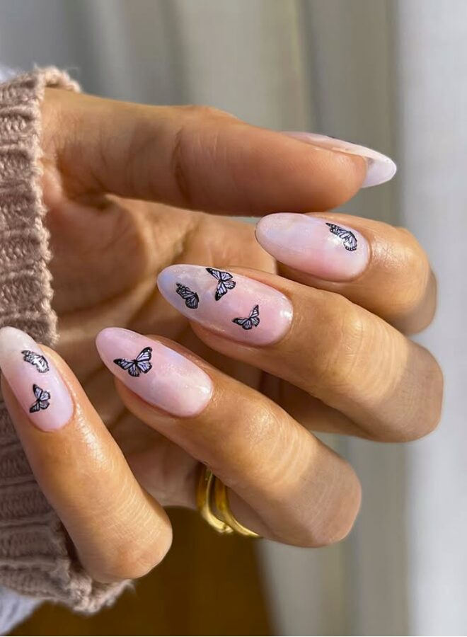 soft pink nails decorated with tiny black butterfly decals