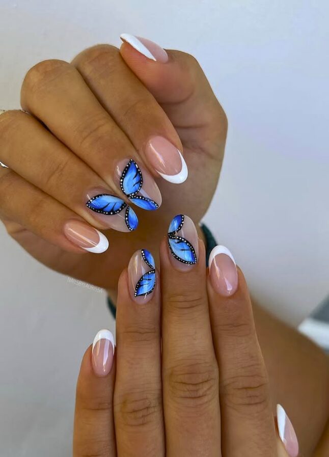 French tip nails with bright blue butterfly wing designs on accent fingers