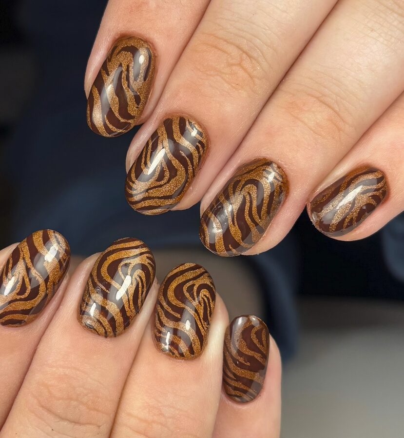 brown nails with shimmering gold swirl patterns
