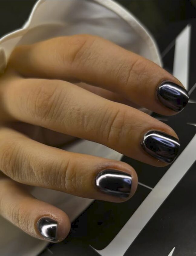 short nails with a glossy black chrome finish, creating a smooth mirror-like metallic effect