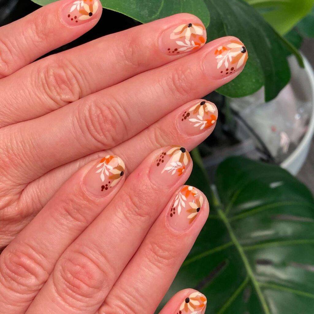 nails with tiny fall-colored floral and leaf designs in orange, white, and brown