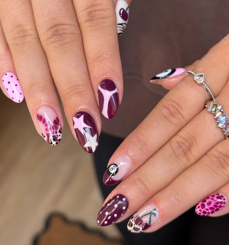 Burgundy and pink nails with stars, polka dots, animal print, and mixed abstract designs