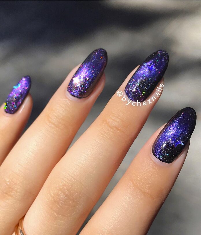 Close-up of oval nails with a galaxy chrome design featuring deep purple and black tones