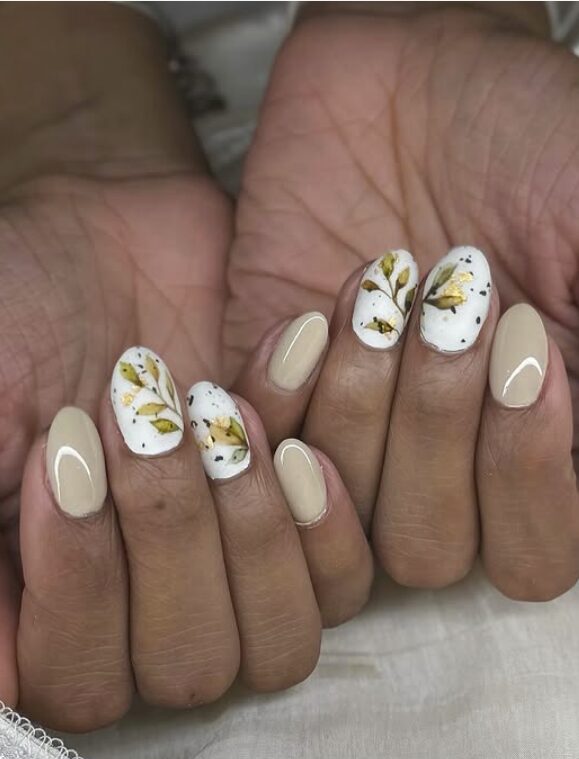 Beige and white nails with delicate gold and green leaf designs