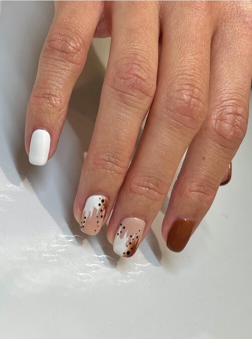 Short nails with white, nude, and brown polish featuring dotted coffee-inspired accents