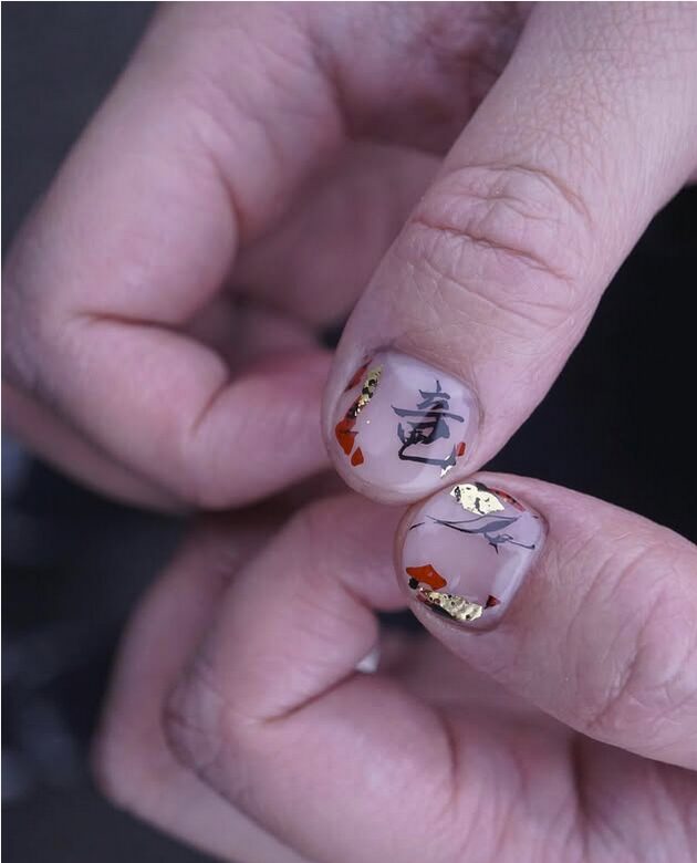 nails with kanji-style calligraphy and gold foil accents