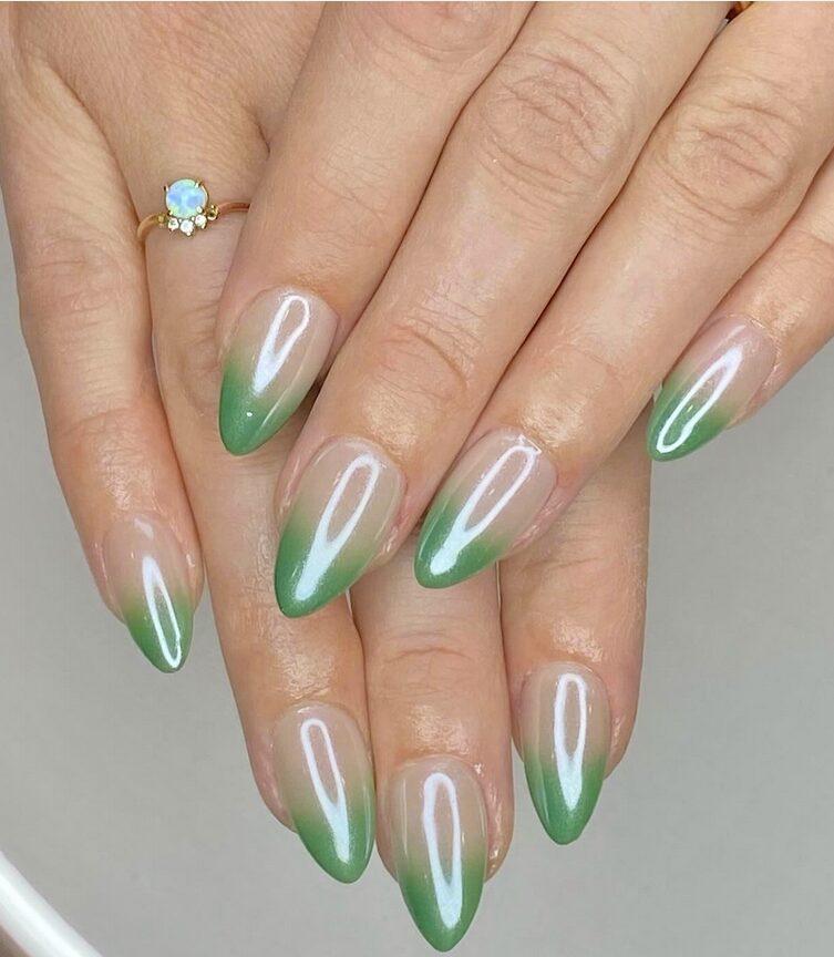 Green ombre nails with a sheer nude base fading into glossy pastel green tips