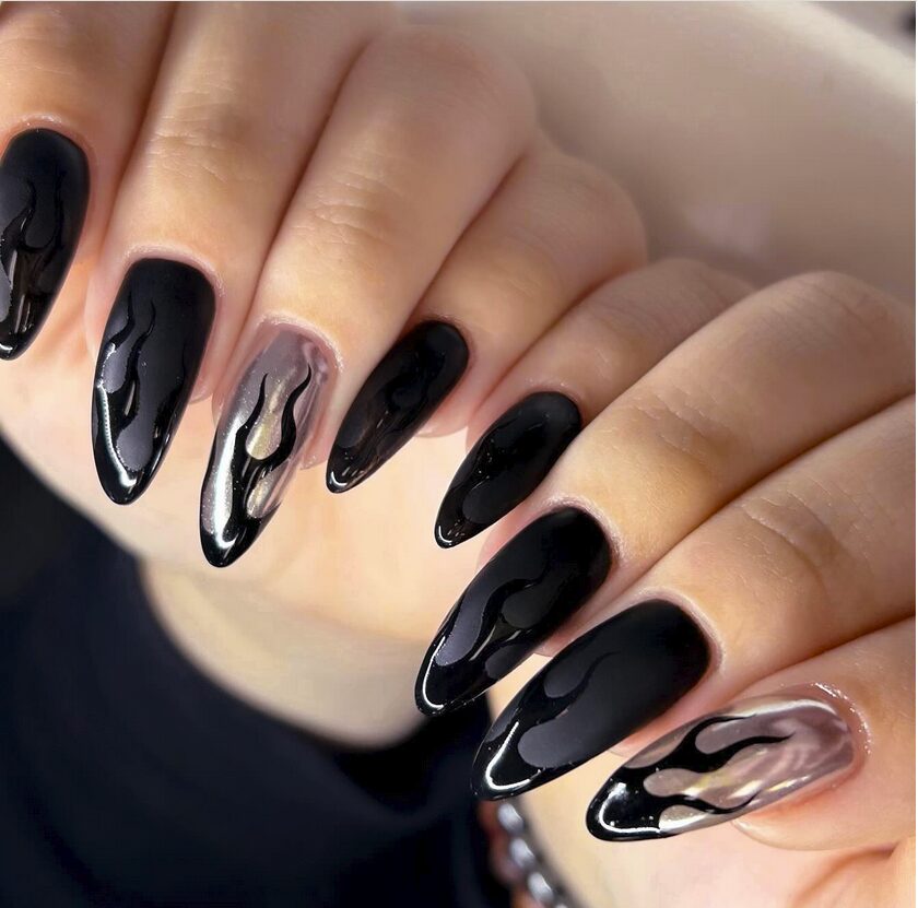 Close-up nails featuring glossy black flame designs over a matte chrome base