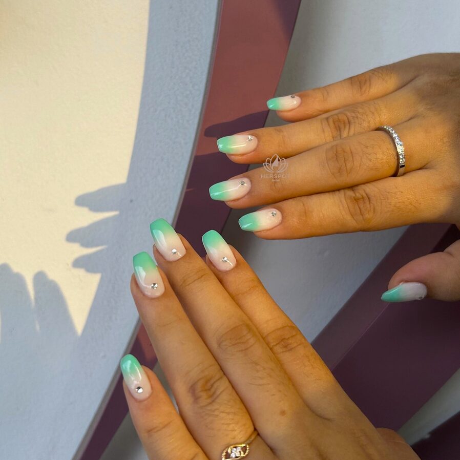 Mint green ombre nails with a soft white base and tiny crystal accents