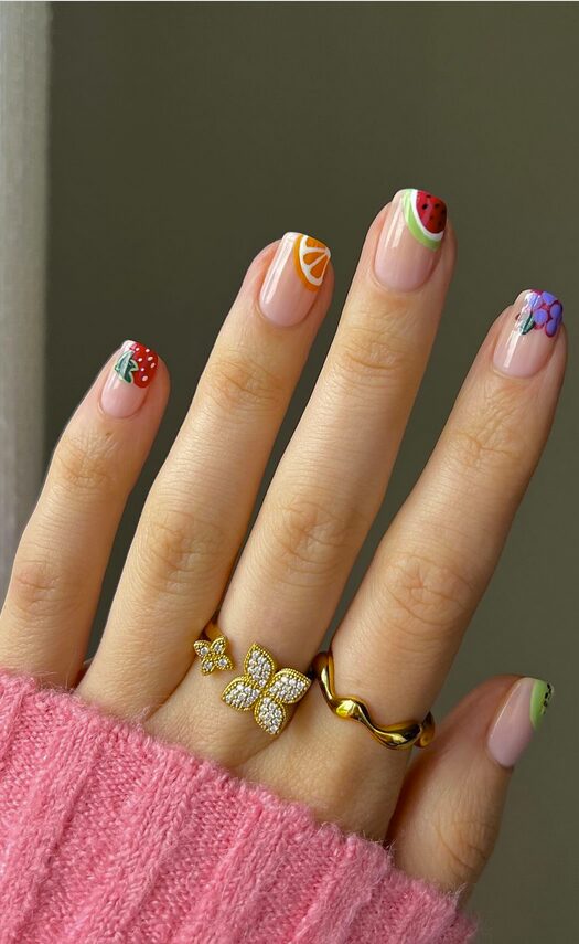 Nude nails with colorful fruit-themed French tips