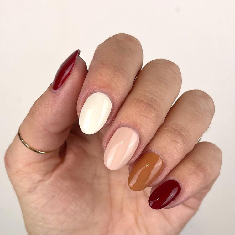 multi-tone manicure featuring deep red, ivory, nude, caramel, and burgundy shades