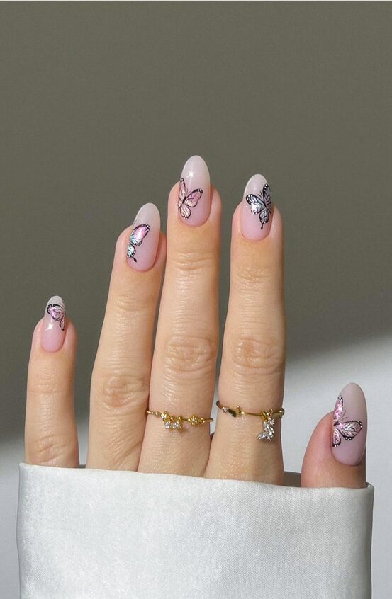 Hand with soft pink nails featuring delicate pastel butterfly decals