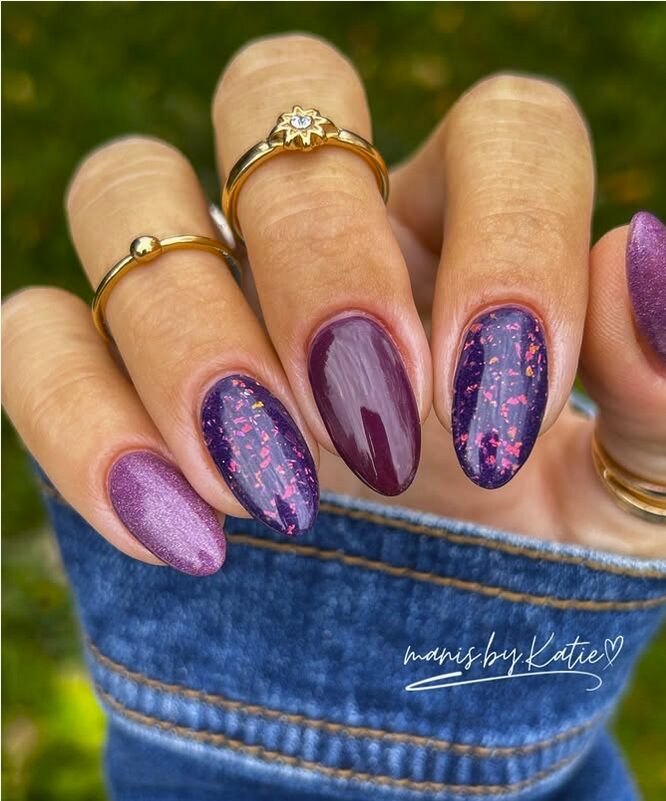 Dark purple almond nails with glitter flakes and shimmer accents
