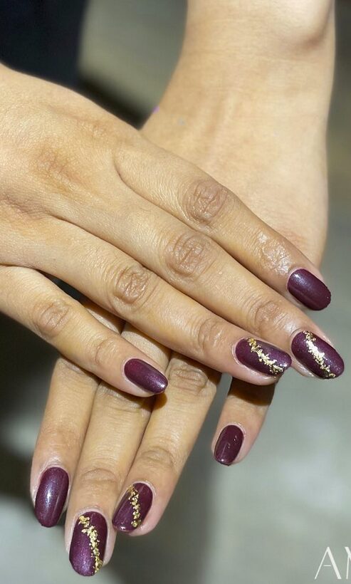 Deep plum nails with gold foil accents