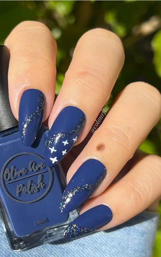 Long navy blue nails with glitter accents and white star designs