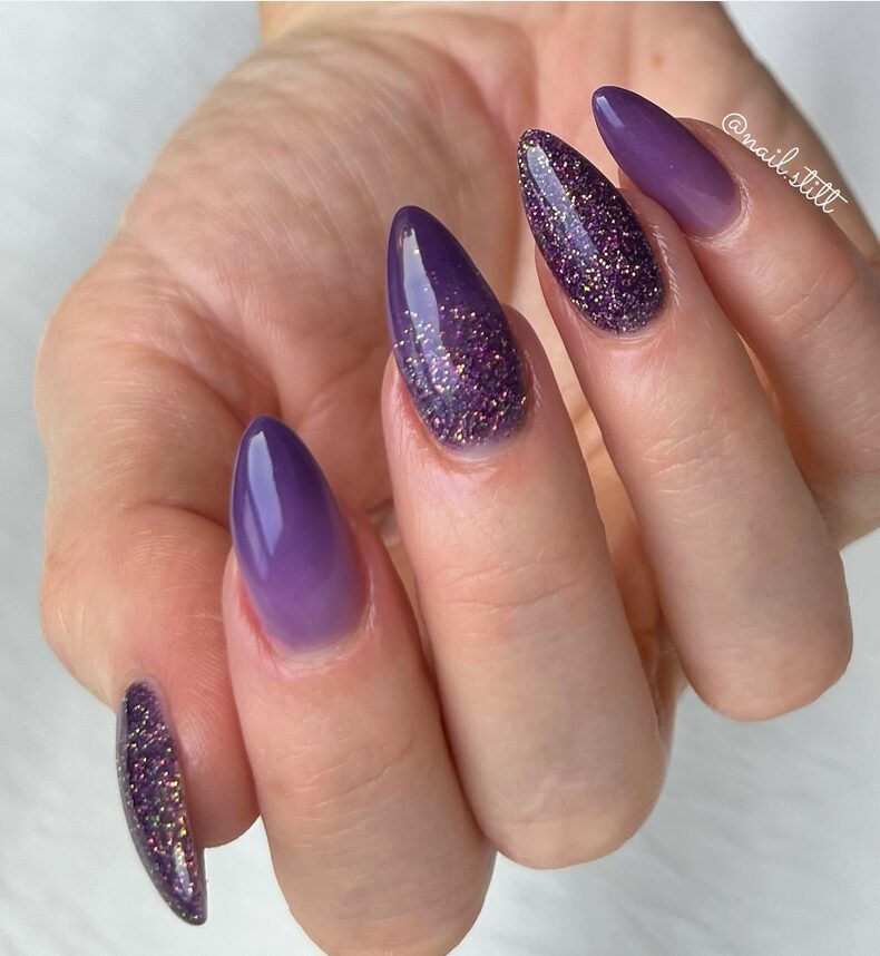 Purple almond nails with glitter accents and a glossy finish