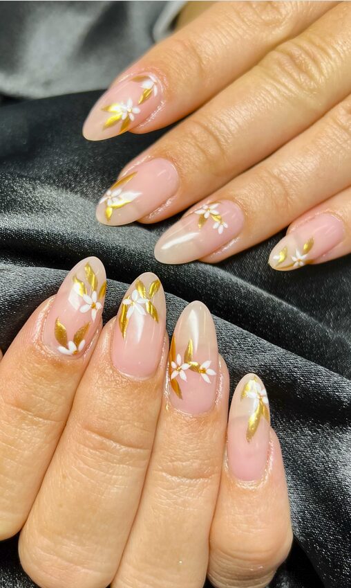 nude nails with gold leaf accents and small white floral details