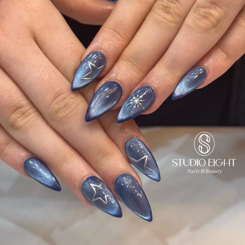 Shimmery midnight blue cat-eye nails with white star accents