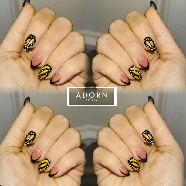 Yellow and black butterfly wing nail art with white dotted accents
