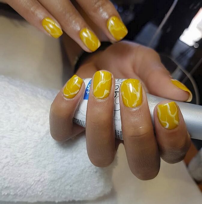 Yellow nails with white marble effect and glossy finish