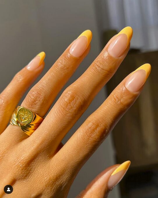 Nude almond nails with bright yellow French tips