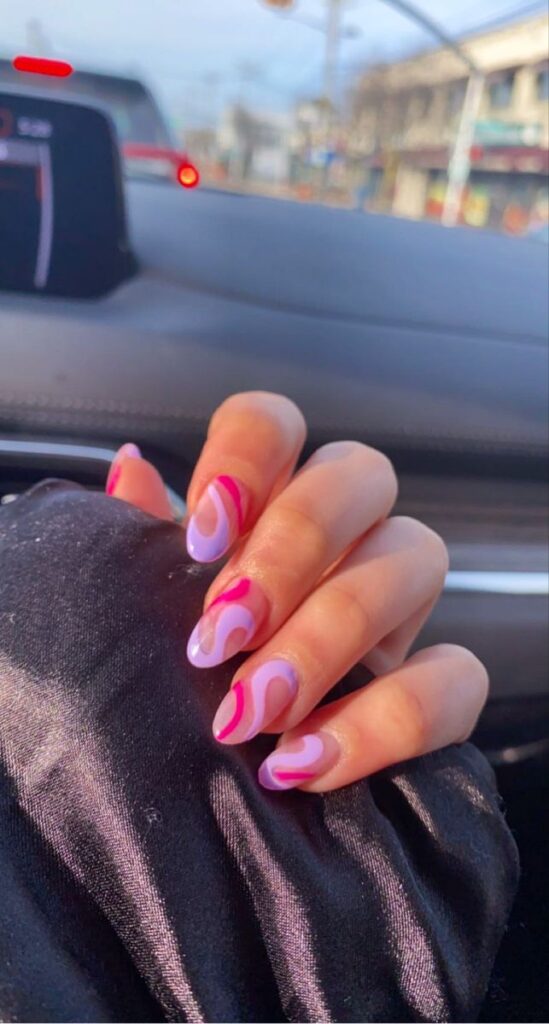Lavender nails with pink and white swirl designs on almond-shaped tips