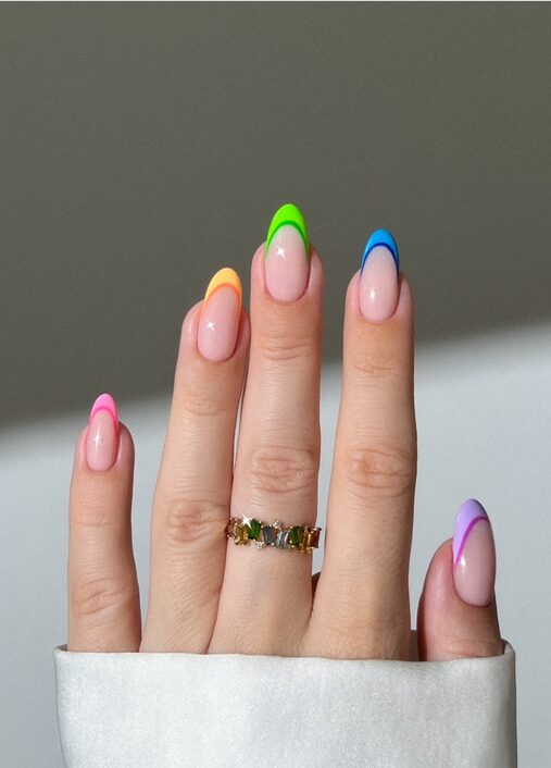 Hand with multicolored neon French tip nails in pink, orange, green, blue, and purple