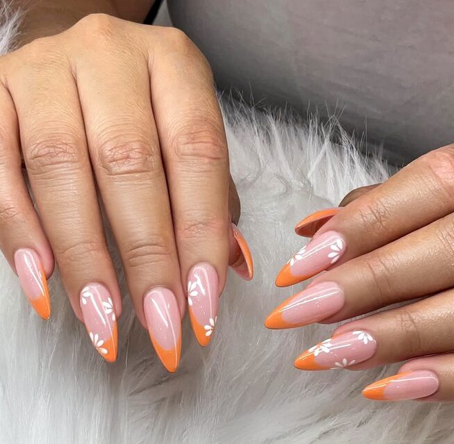 Bright orange nails with small white floral art