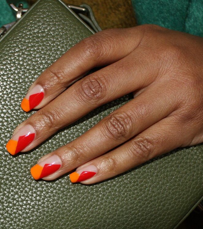 Hand with glossy geometric red and orange nail art