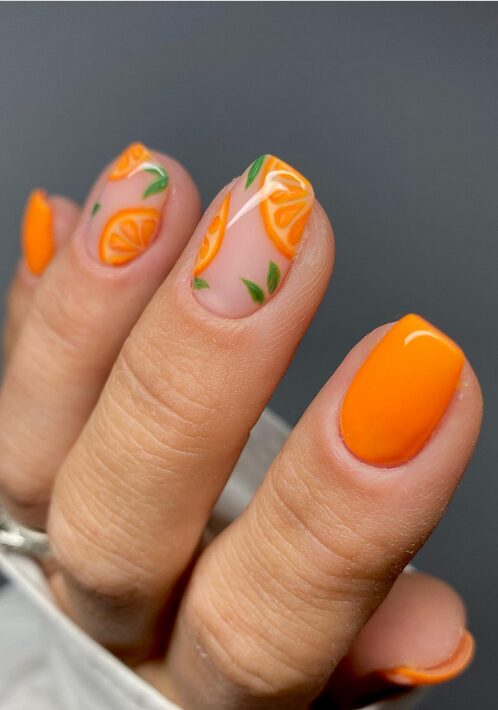 Orange nail art with citrus slice designs on a nude base