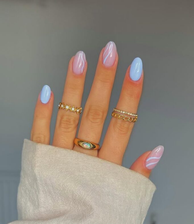 Pastel blue nails with soft pink bases and white swirl accents