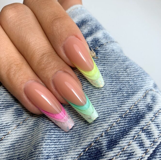 nails with a nude base and pastel rainbow French tips