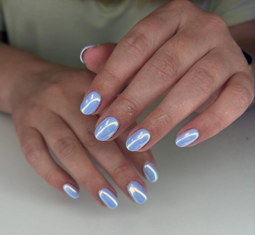 Shimmery periwinkle chrome nails with a glossy, reflective finish on short rounded nails