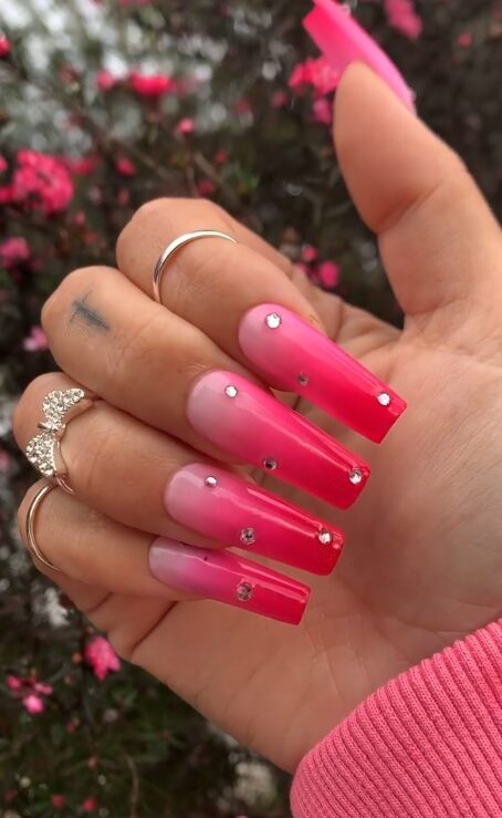 nails with a pink ombre gradient and rhinestone accents