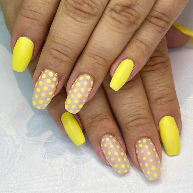 Yellow nails with nude accents featuring playful yellow polka dots.