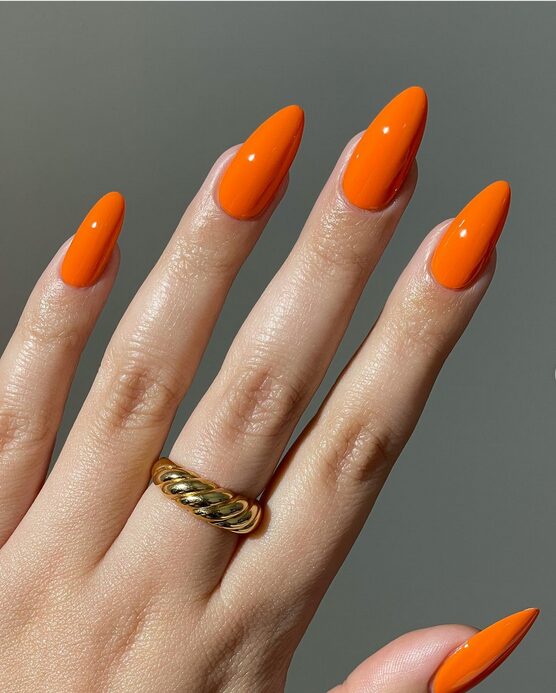 Bright sunset orange almond nails with a glossy finish